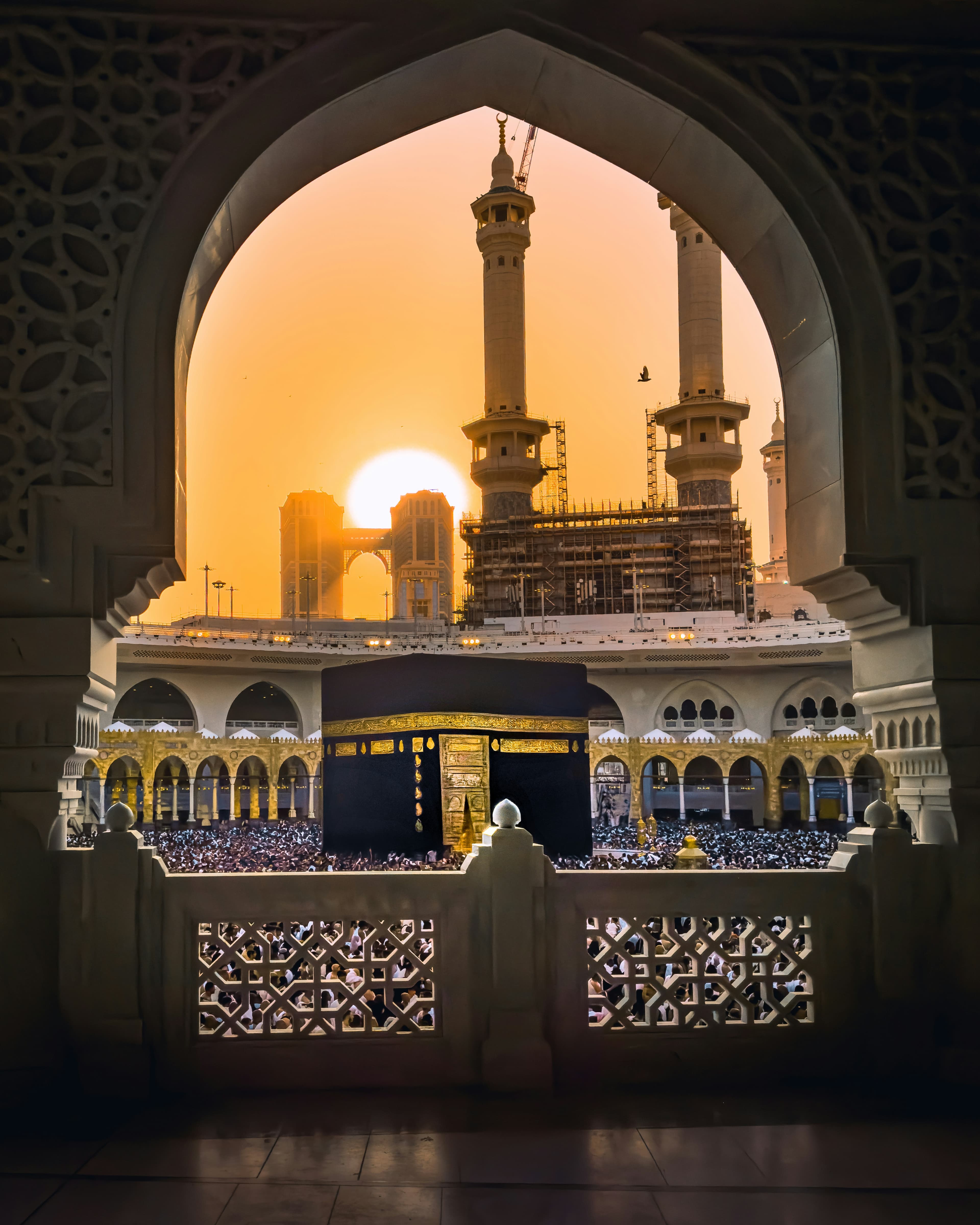 The Kaaba at sunset, framed by an ornate archway of Masjid al-Haram