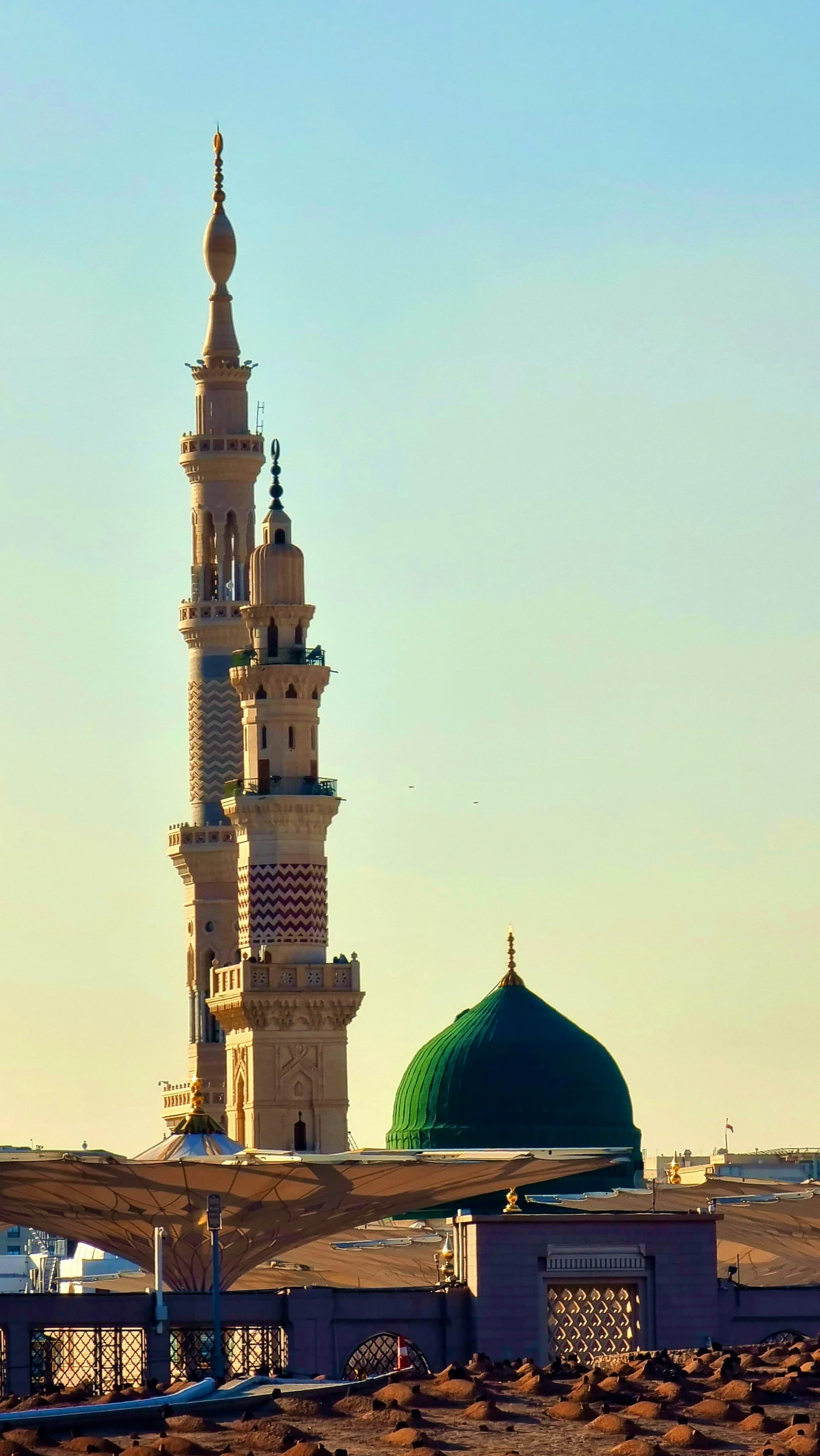 A minaret and the green dome of Masjid an-Nabawi against a clear sky